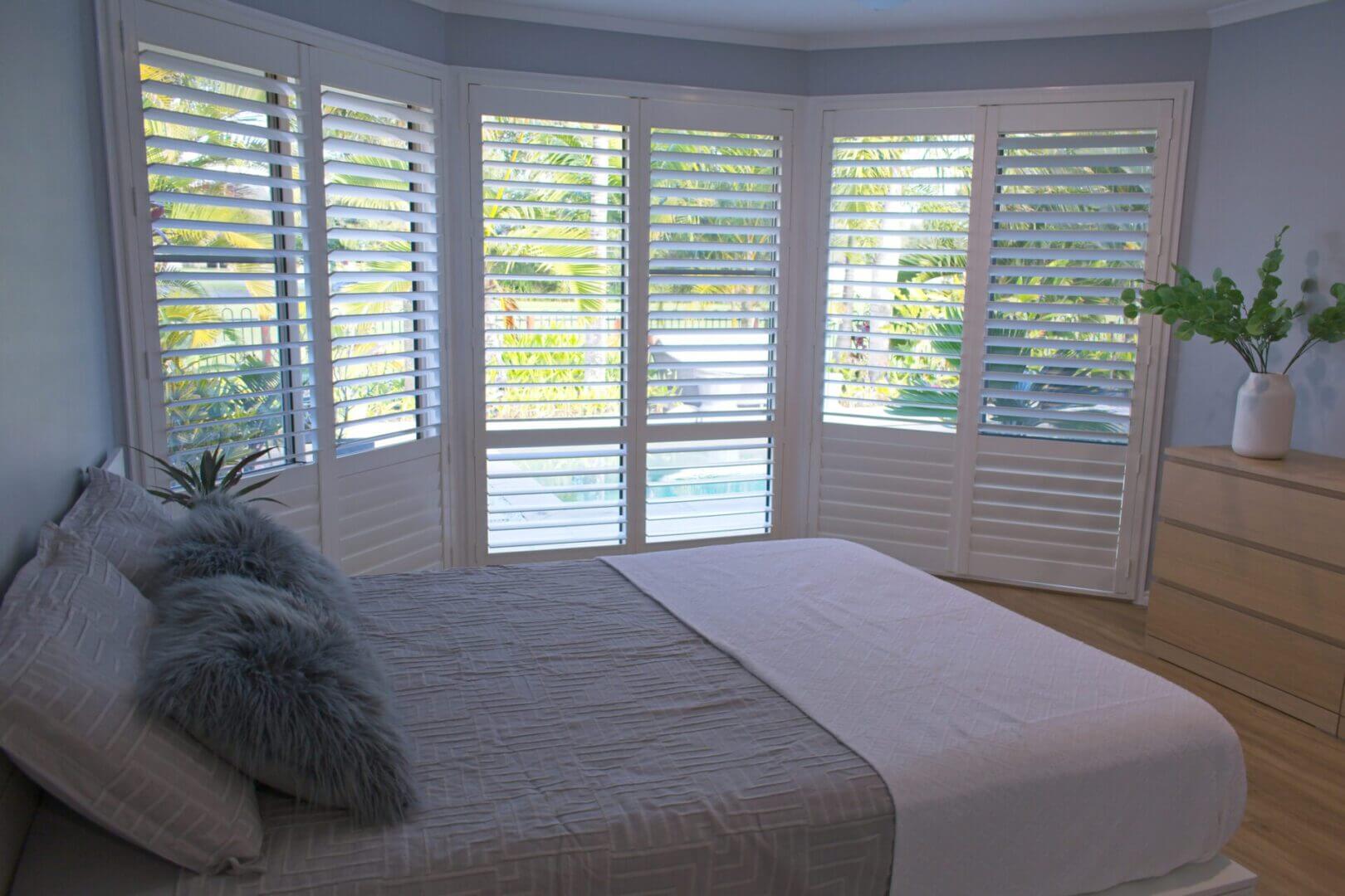 Bedroom with large windows and white shutters.